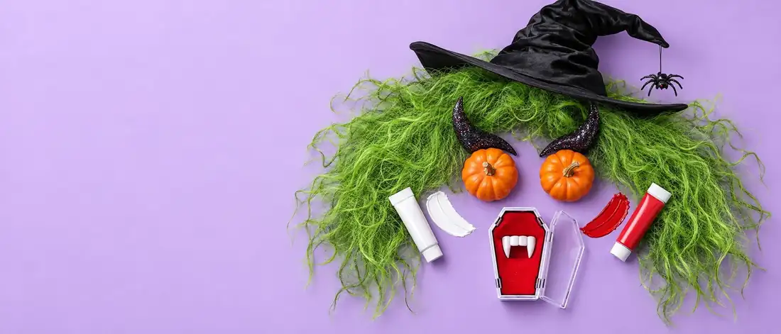 Ett monsteransikte av Halloweentillbeh&ouml;r: gr&ouml;n peruk, h&auml;xhatt, pumpa&ouml;gon, horn och vampyrt&auml;nder
